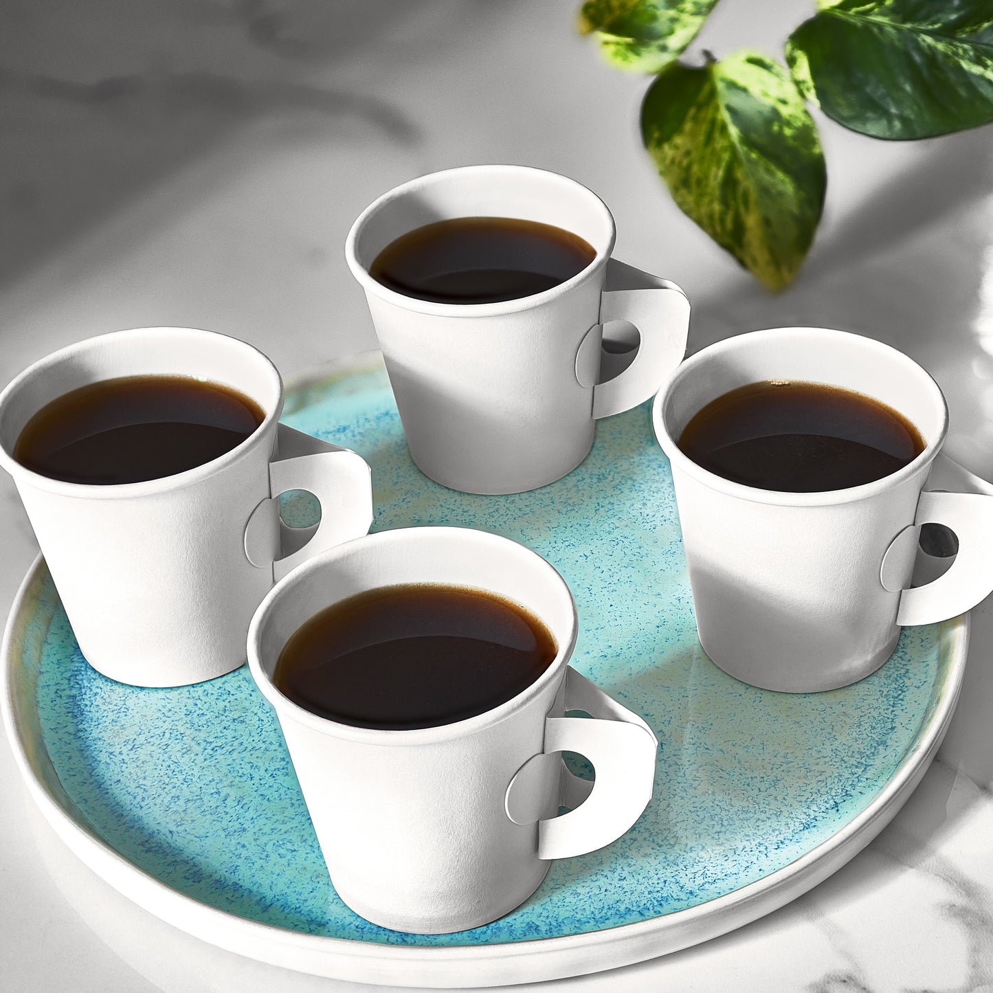 Four white coffee cups with dark liquid on a turquoise tray